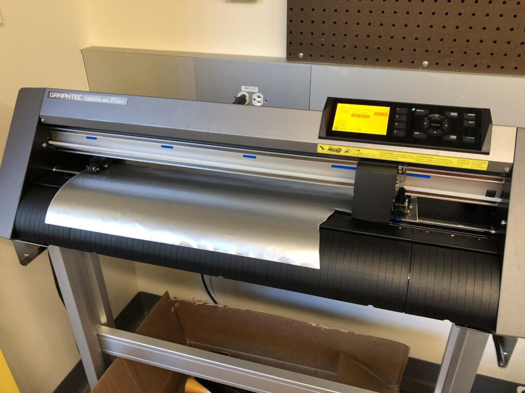 Partially cut vinyl loaded into the machine, with the clean edge lined up to the guideline, Northeastern Makerspaces