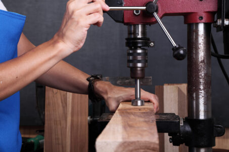 Person drilling with a forstner bit and drill press_Northeastern makerspaces