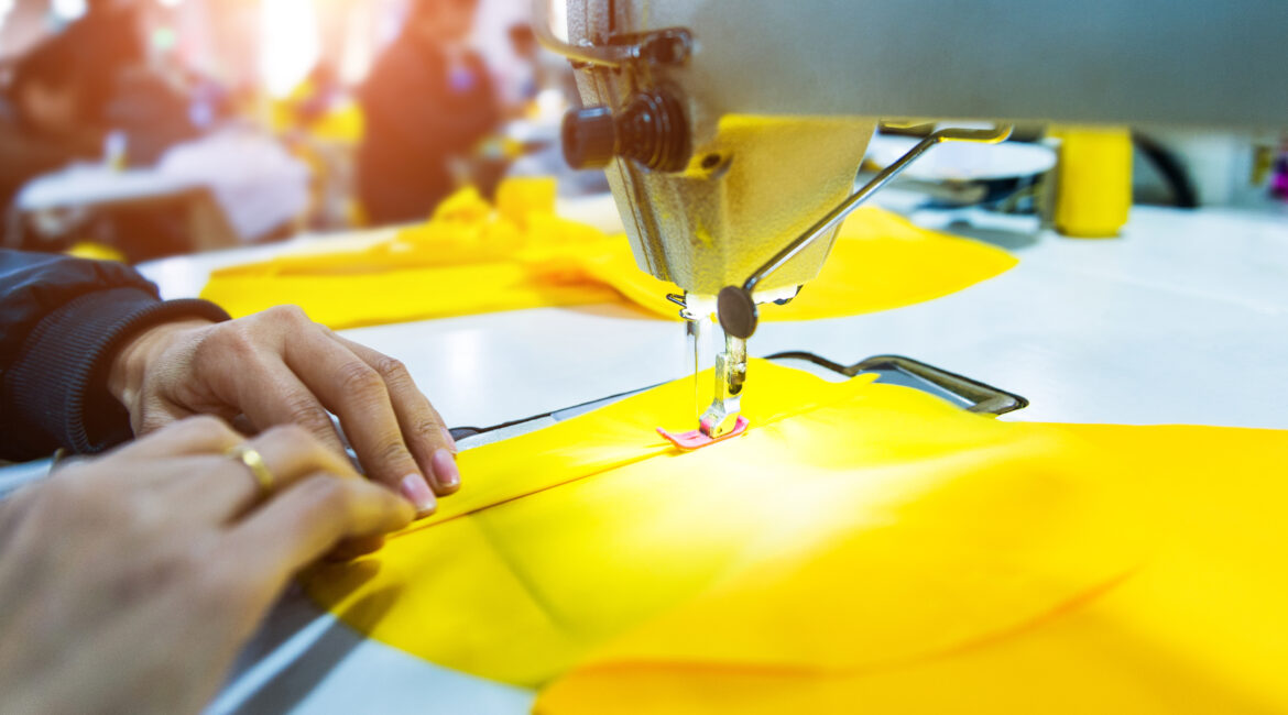 Hands sewing on a yellow fabric