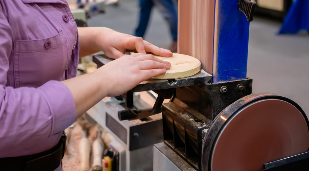 Person sanding a curved edge on a belt-disc sander