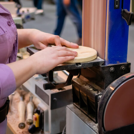 Person sanding a curved edge on a belt-disc sander