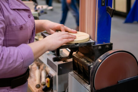 Person sanding a curved edge on a belt-disc sander