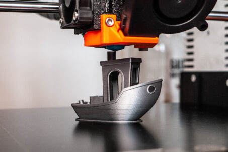 3D printer printing a model boat in silver filament