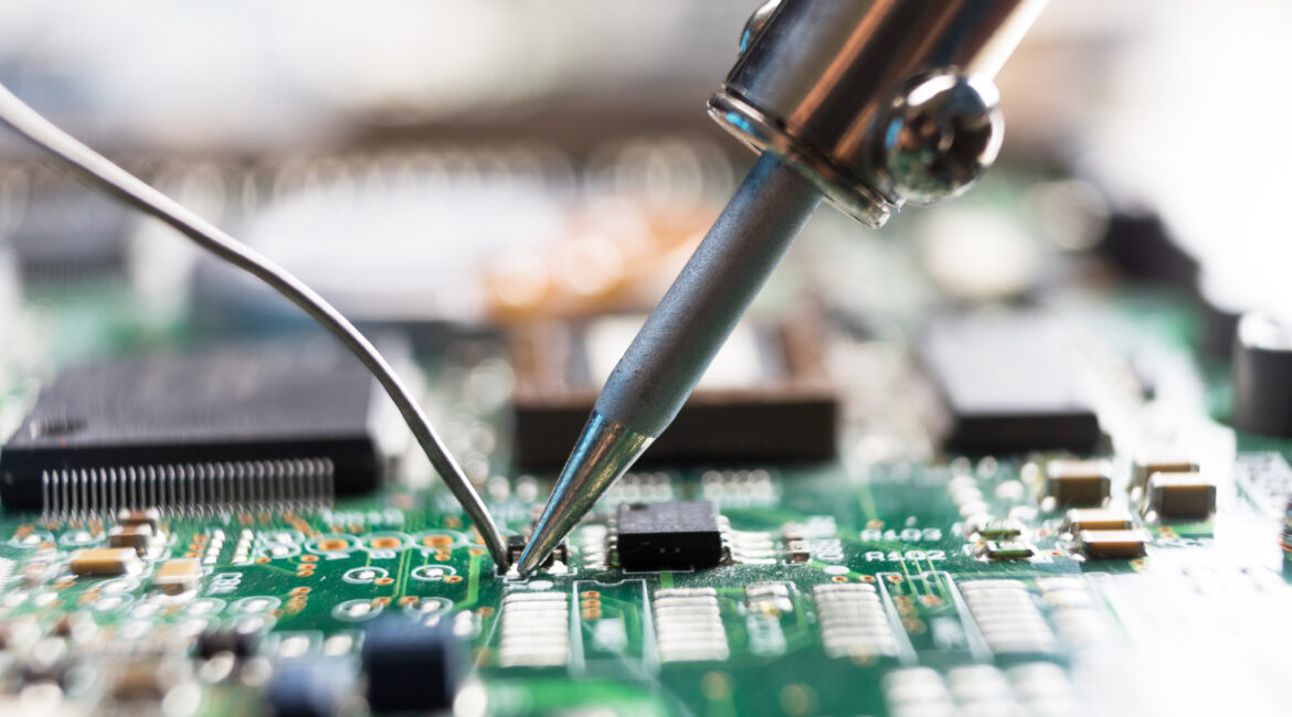 The hand holding the tin, a soldering iron solder the chip in place.