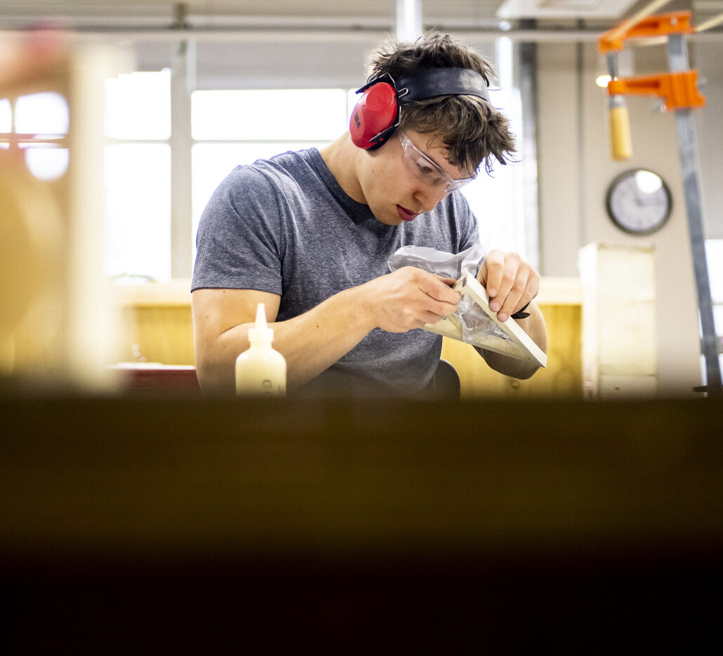 Student wearing sound reducing earmuffs engages with materials and equipment 