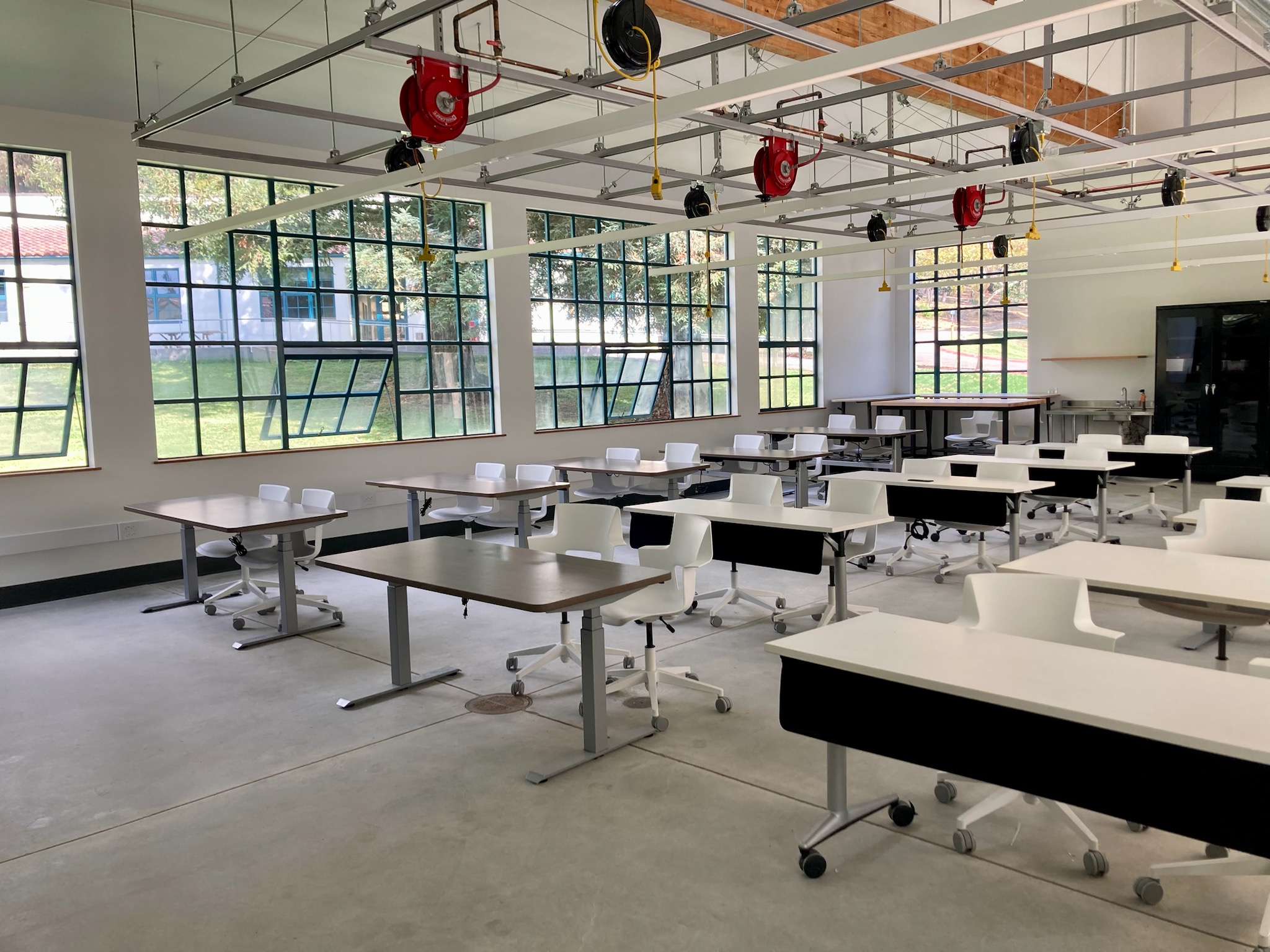 Classroom with windows, many desks and chairs.