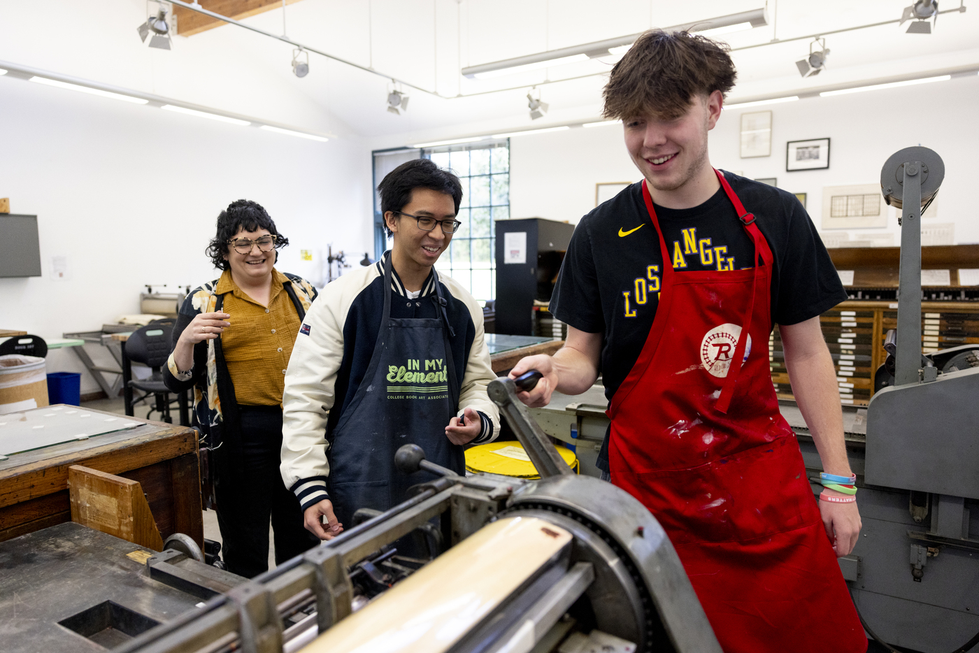 Two students work in the Analog Print Lab while being helped by staff.