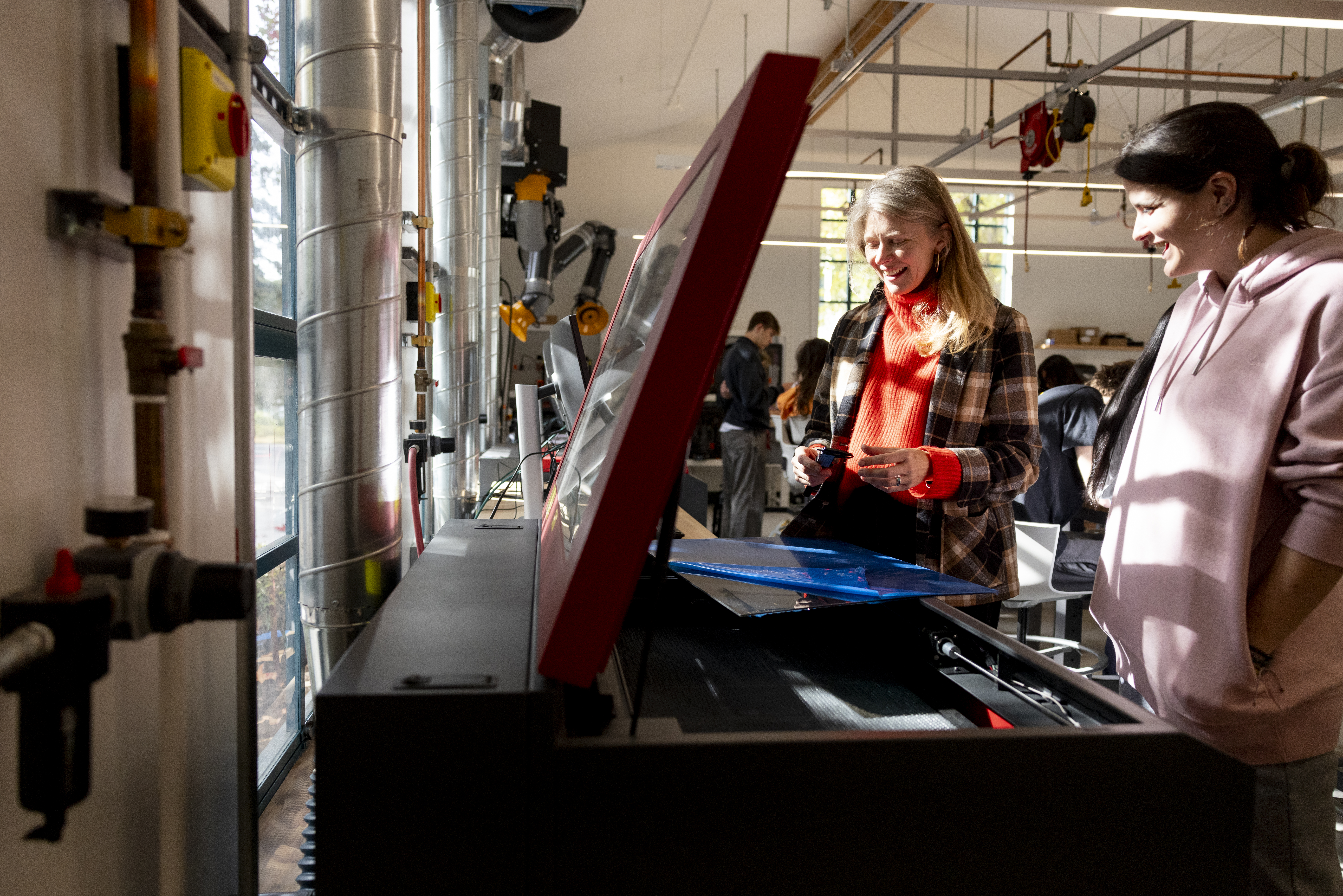 Oakland Makerspace A staff member helps a student with a laser cutter.