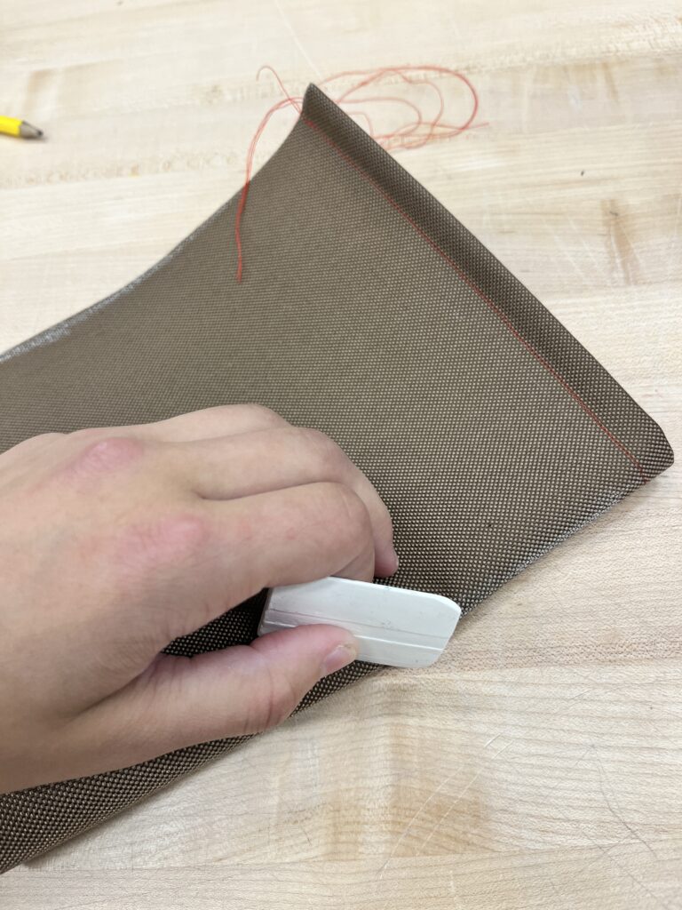 hand holding white chalk over brown fabric