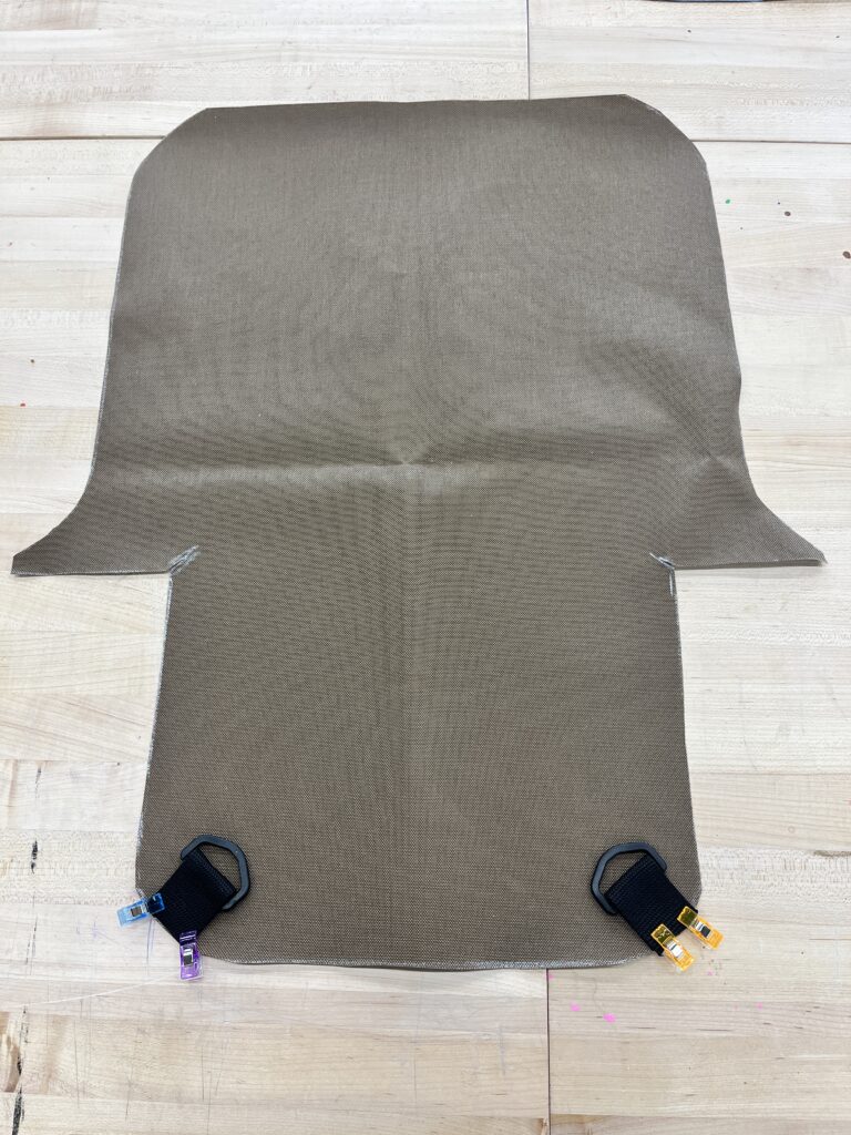 Large brown fabric with shoulder strap and D rings clipped to the bottom