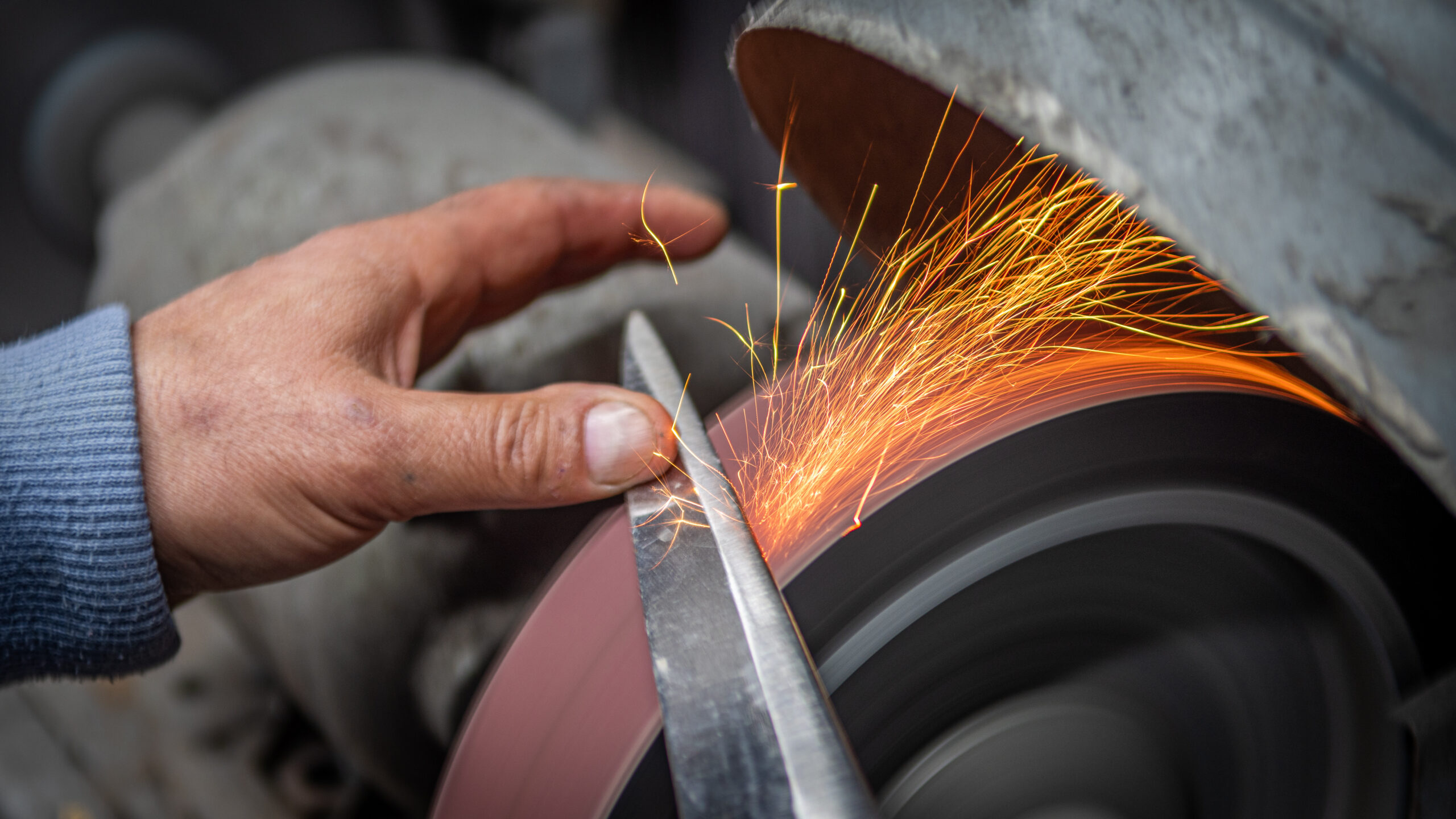 Person sharpening a knife on a grinding wheel.
