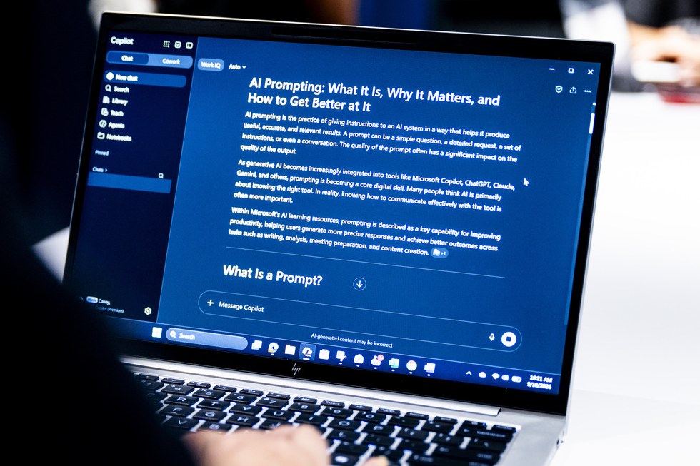 A student reading an article about AI prompting on a laptop at the AI Makerspace